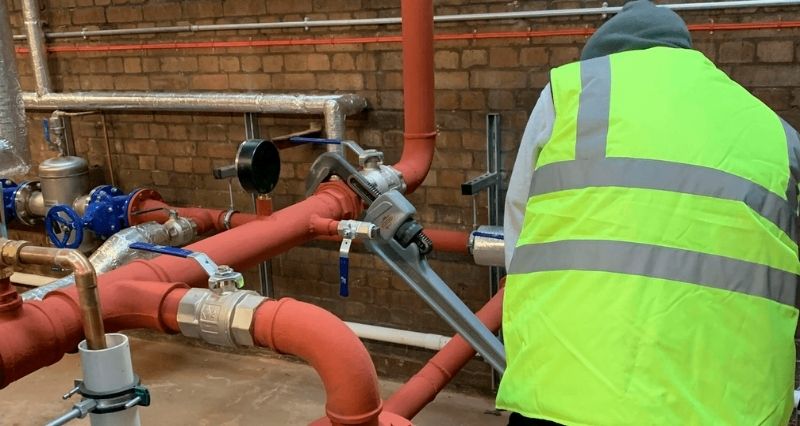 Engineer installing temporary boiler pipework to restore heating at a school