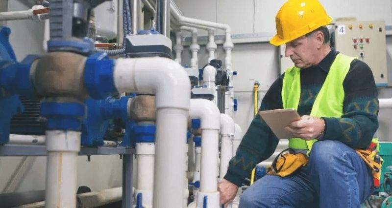 Engineer inspecting temporary boiler pipework during an emergency heating installation