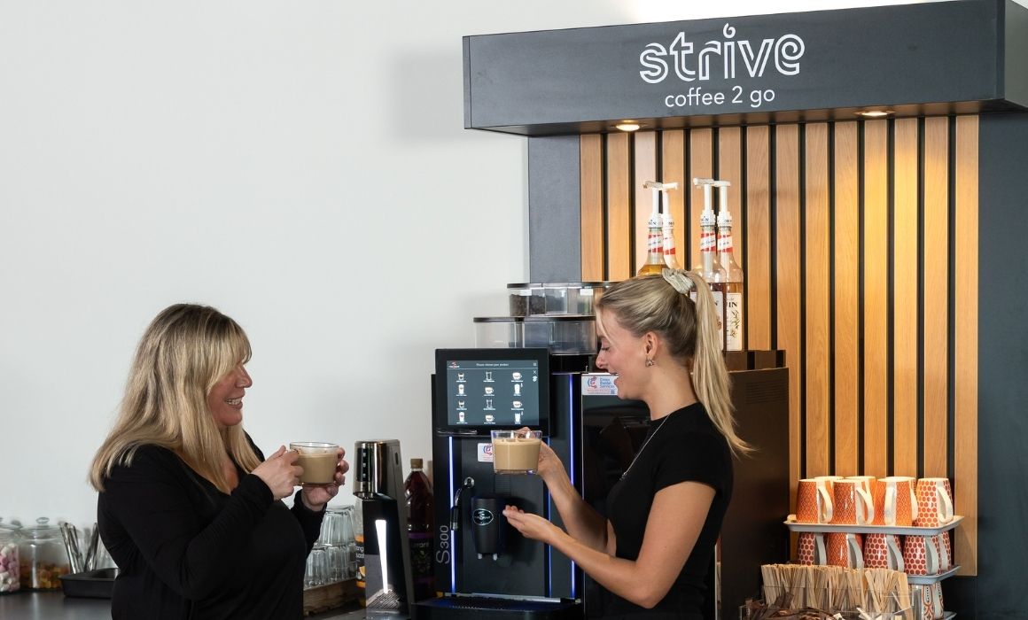wo women smiling and drinking fresh coffee from a Strive bean-to-cup office coffee station